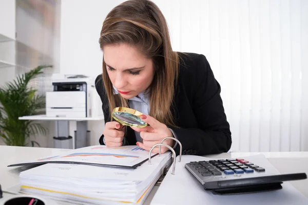 Empresária examinando fatura com lupa — Fotografia de Stock