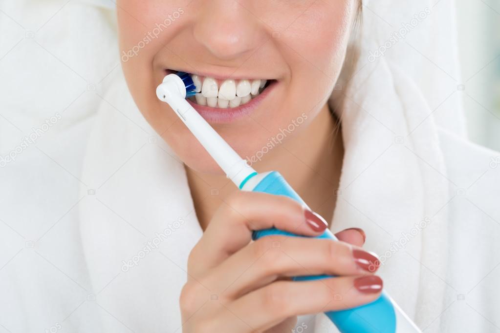 Woman In Bathrobe Brushing Teeth
