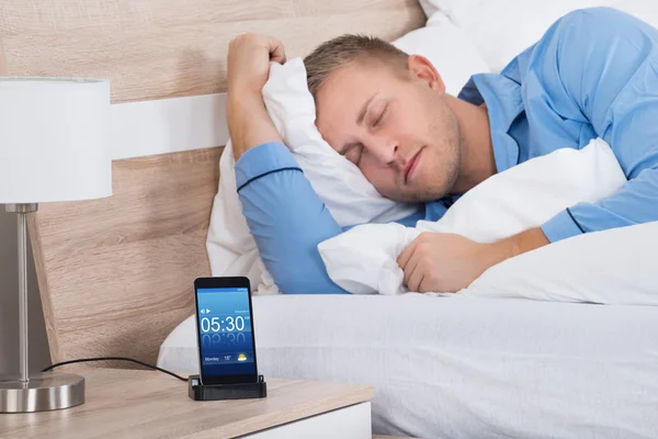 Alarm ile cep telefonu üzerinde uyuyan adam — Stok fotoğraf
