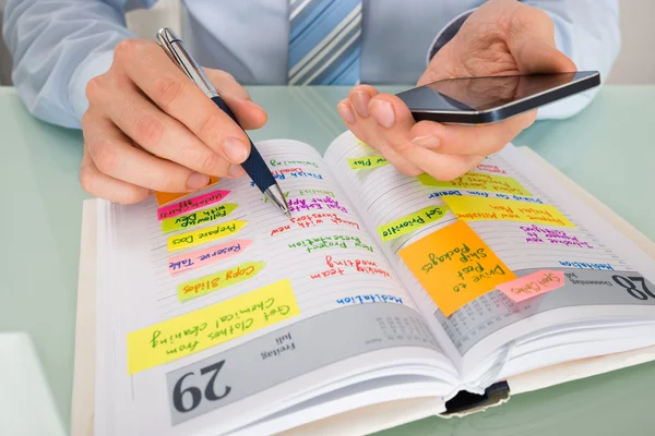 Geschäftsmann schreibt Fahrplan ins Tagebuch — Stockfoto