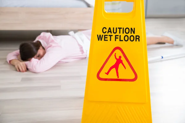 Wet Floor Sign With Fainted Housekeeper — Stock Photo, Image