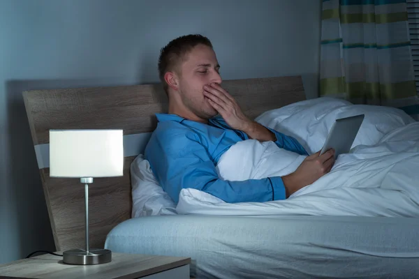 Man met Laptop in Bed geeuwen — Stockfoto