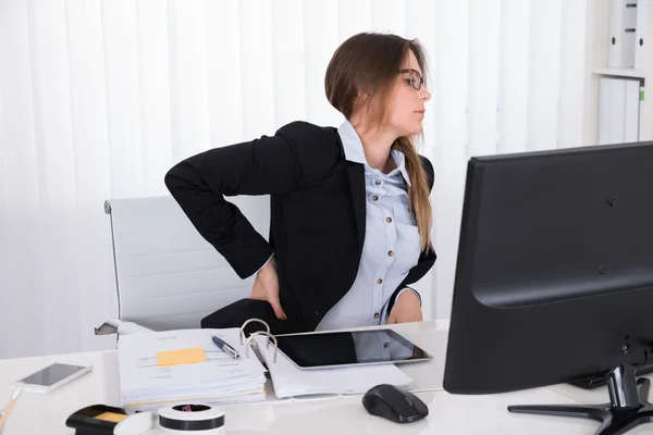 Empresaria en silla con dolor de espalda —  Fotos de Stock