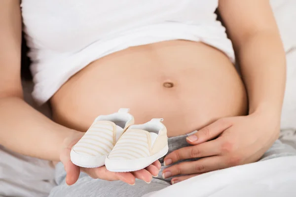 Kobieta w ciąży z dziecięcymi butami — Zdjęcie stockowe