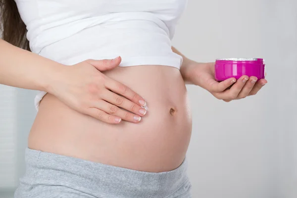 Mujer embarazada aplicando crema —  Fotos de Stock