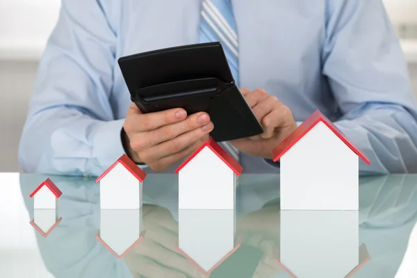 Businessman with Calculator and House Models — Stock Photo, Image