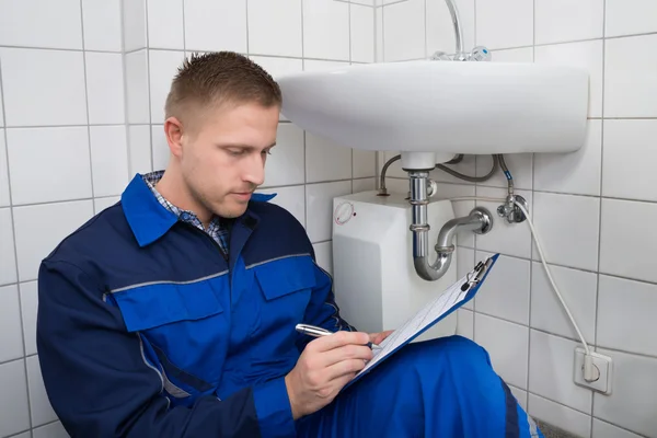 Young Plumber Writing On Clipboard — Stock Photo, Image