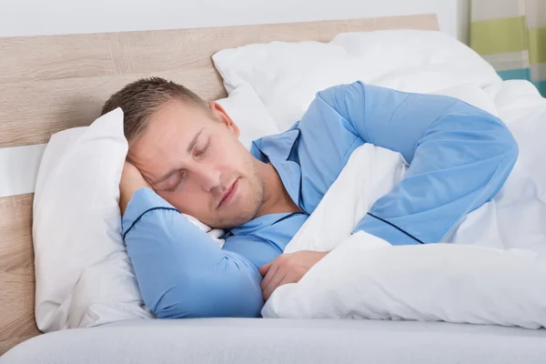 Muž spí na posteli — Stock fotografie