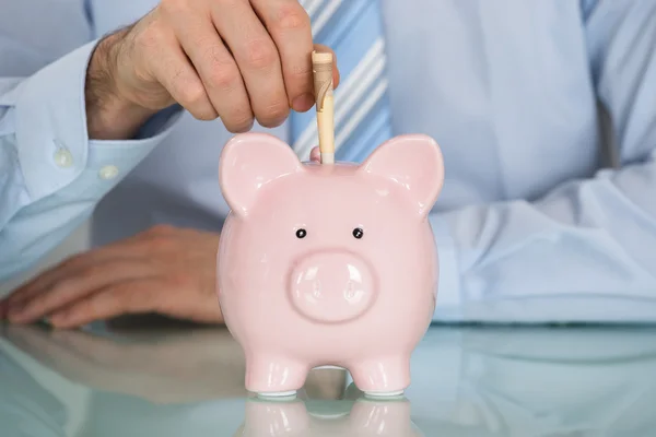 Businessman Inserting banknote in Piggy Bank — Stock Photo, Image