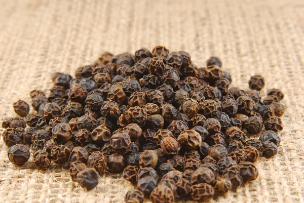 Black pepper on hessian fabric — Stock Photo, Image
