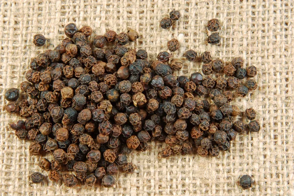 Black pepper on hessian fabric — Stock Photo, Image