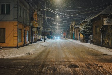 Cacak, Sırbistan - 04 Ocak 2026: İlk kar ve trafik sorunlarının yaşandığı kent merkezi yakınlarındaki gece sokak sahnesi.