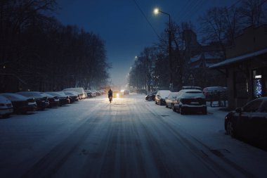 Geceleyin karla kaplı bir sokakta bisikletçi, Sırbistan 'ın Cacak kentinde.