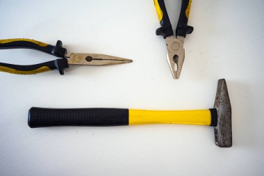 Sarı siyah çekiç ve maşa, beyaz yüzeyde soyut kompozisyon.