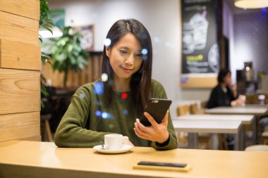 Café'de cep telefonu kullanan kadın