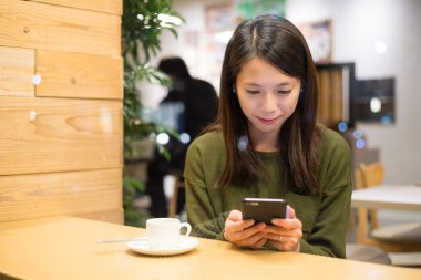 Café'de cep telefonu kullanan kadın