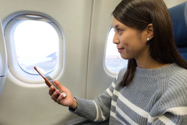 Vrouw met behulp van mobiele telefoon in vliegtuig — Stockfoto