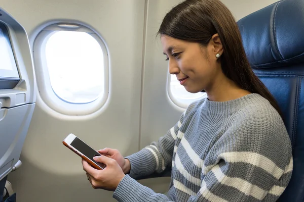 Vrouw met behulp van mobiele telefoon in vliegtuig — Stockfoto