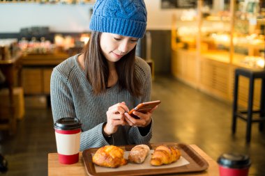 Asyalı kadın cep telefonu kafede kullanarak