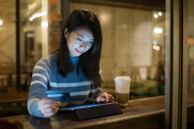 Kafede tablet kullanan Asyalı kadın.