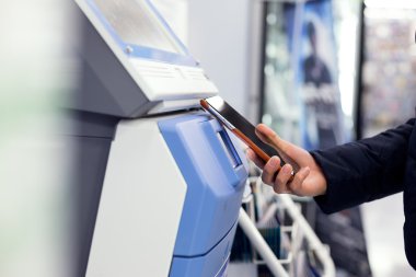 Woman paying on ticketing machine by cell phone
