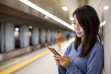 Yeraltı metro istasyonuna cep telefonu kullanan kadın