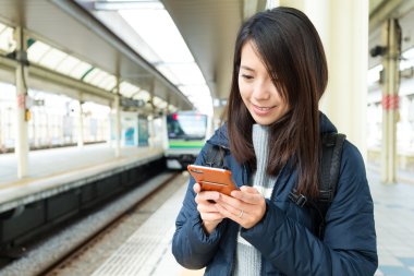 Tren platformu üzerinde cep telefonu kullanan kadın