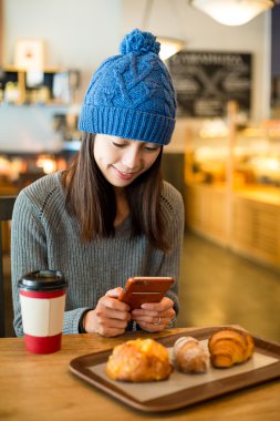 Asyalı kadın cep telefonu kafede kullanarak
