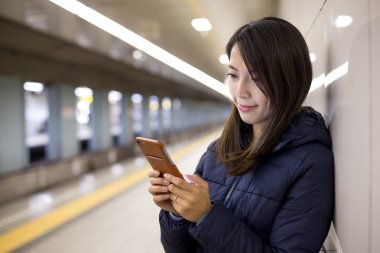 Yeraltı metro istasyonuna cep telefonu kullanan kadın