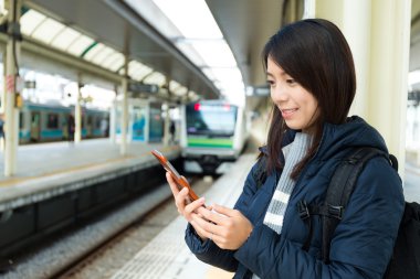 Tren platformu üzerinde cep telefonu kullanan kadın