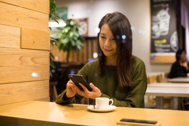 Kahve dükkanında cep telefonu kullanan kadın