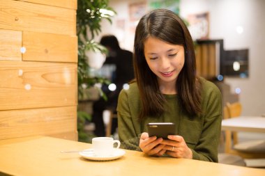 Kahve dükkanında cep telefonu kullanan kadın