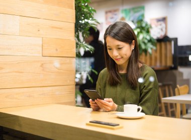 Kahve dükkanında cep telefonu kullanan kadın