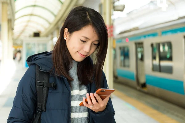 Жінка використовує мобільний телефон на залізничній платформі — стокове фото