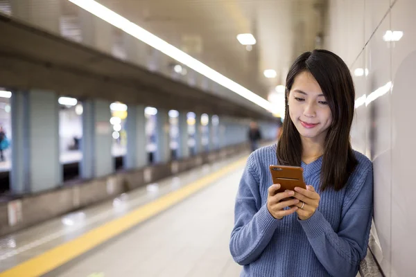 Mujer usando teléfono celular en estación de metro subterráneo — Foto de Stock