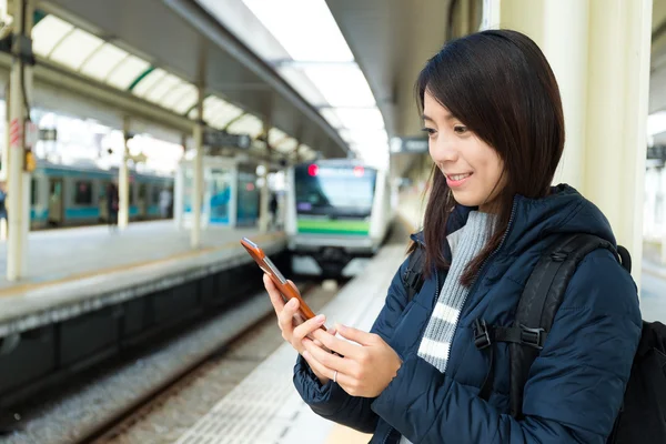 Жінка використовує мобільний телефон на залізничній платформі — стокове фото