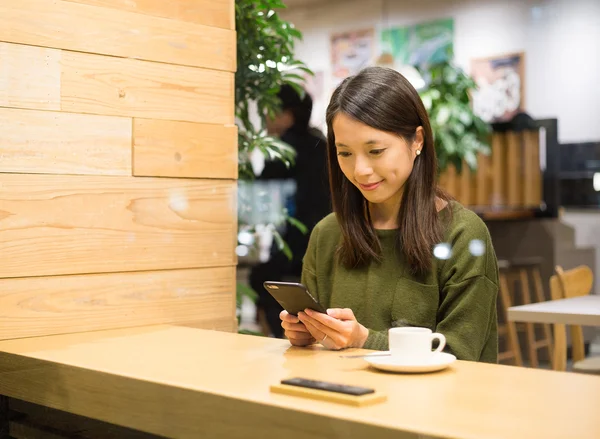 Kahve dükkanında cep telefonu kullanan kadın