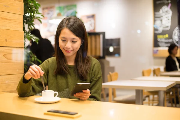 Женщина наслаждается кофе и держит мобильный телефон — стоковое фото