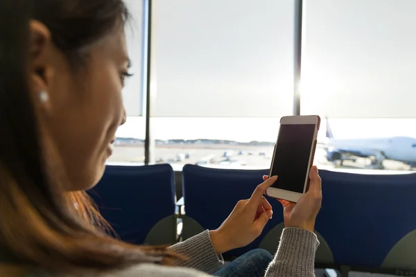 Vrouw met behulp van mobiele telefoon in de vertrekhal van luchthaven — Stockfoto