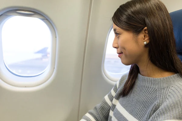 Woman looking out of the window in airplane — Stock Photo, Image