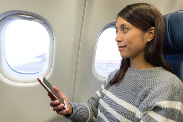 Vrouw met behulp van de mobiele telefoon in vliegtuig — Stockfoto