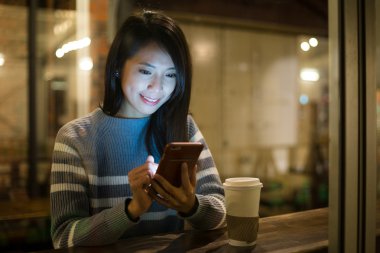 Kahve dükkanında cep telefonu kullanan kadın