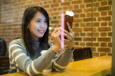 Kahve dükkanında cep telefonu kullanan kadın