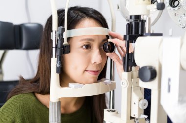 Woman checking vision at eye clinic clipart