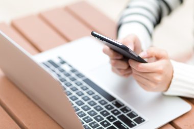 Dizüstü bilgisayar ve cep telefonu kullanan kadın