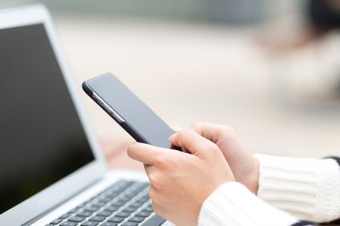 Dizüstü bilgisayar ve cep telefonu kullanan kadın