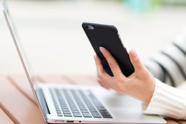 Dizüstü bilgisayar ve cep telefonu kullanan kadın
