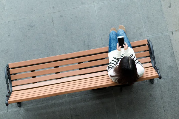 Mujer en el banco usando el teléfono móvil —  Fotos de Stock