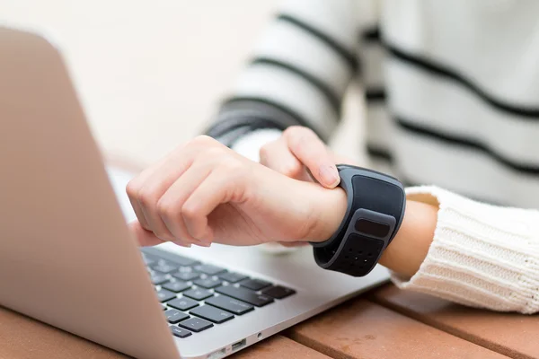 Woman connecting smart watch with laptop