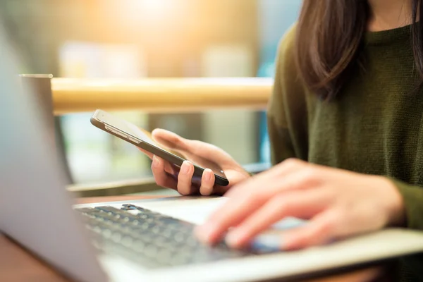 Mulher usando telefone celular e laptop — Fotografia de Stock